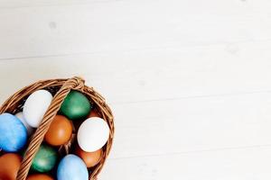 painted Easter eggs in a basket on a light background top view photo