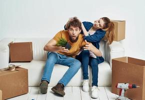 cheerful man and woman on the couch moving interior cardboard boxes photo