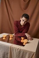 el chico en un paño antecedentes se sienta a un mesa con un espejo y maduro naranjas habitación modelo foto