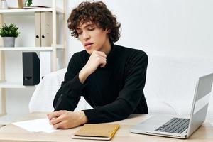 curly guy sitting at the table in a black sweater lessons Lifestyle technology photo