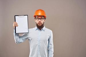 Emotional man wearing orange hard hat on industry documents photo
