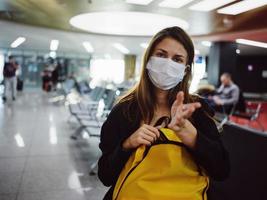 mujer vistiendo médico máscara amarillo mochila aeropuerto esperando para vuelo foto