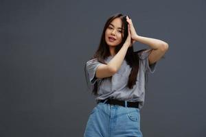 young woman in a t-shirt and jeans posing Youth style Gray background photo