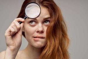 red-haired woman magnifier near the face hygiene close-up photo