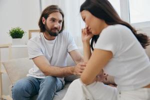 An Asian woman is sad and crying with her male friend at home. Stress and misunderstanding in a relationship between two people and supporting each other's mental and emotional well-being photo