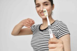 morena en un a rayas camiseta cepillo de dientes en mano ligero antecedentes foto