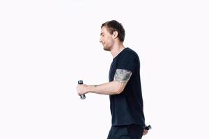 guy in a black t-shirt with dumbbells in his hands on a white background fitness pumped up muscles tattoo photo