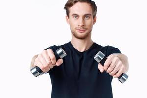 cute young man with dumbbells in hands goes in for sports on white background cropped view photo