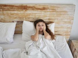 woman lies in bed hands on face emotions lifestyle photo