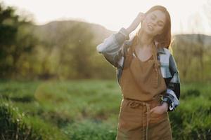 Portrait of a young smiling woman in work clothes checkered shirt and apron in nature in the evening after work photo