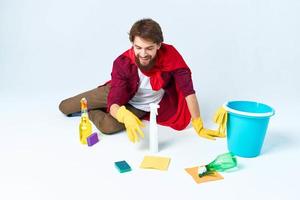 limpiador con limpieza suministros en un rojo impermeable en el piso de el casa interior foto