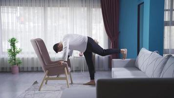 deportista haciendo Lagartijas enérgicamente utilizando sofá y sillón. joven atleta hombre haciendo Lagartijas en silla y sillón. video