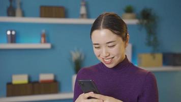 Aziatisch gelukkig vrouw pratend naar iemand Aan haar telefoon. jong schattig Aziatisch vrouw is gelukkig en vrolijk terwijl op zoek Bij haar telefoon. video