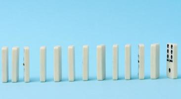 Dominoes standing in a row on a blue background, gambling photo