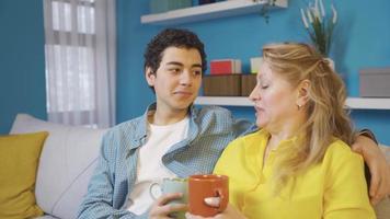 Cheerful and delightful mother and son. Happy mother and son sitting on sofa at home and chatting. video