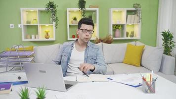 Funny and cheerful man having unfortunate moments in home office, surprised at his clumsiness. Clumsy distracted man is bored and overwhelmed in his home office. video