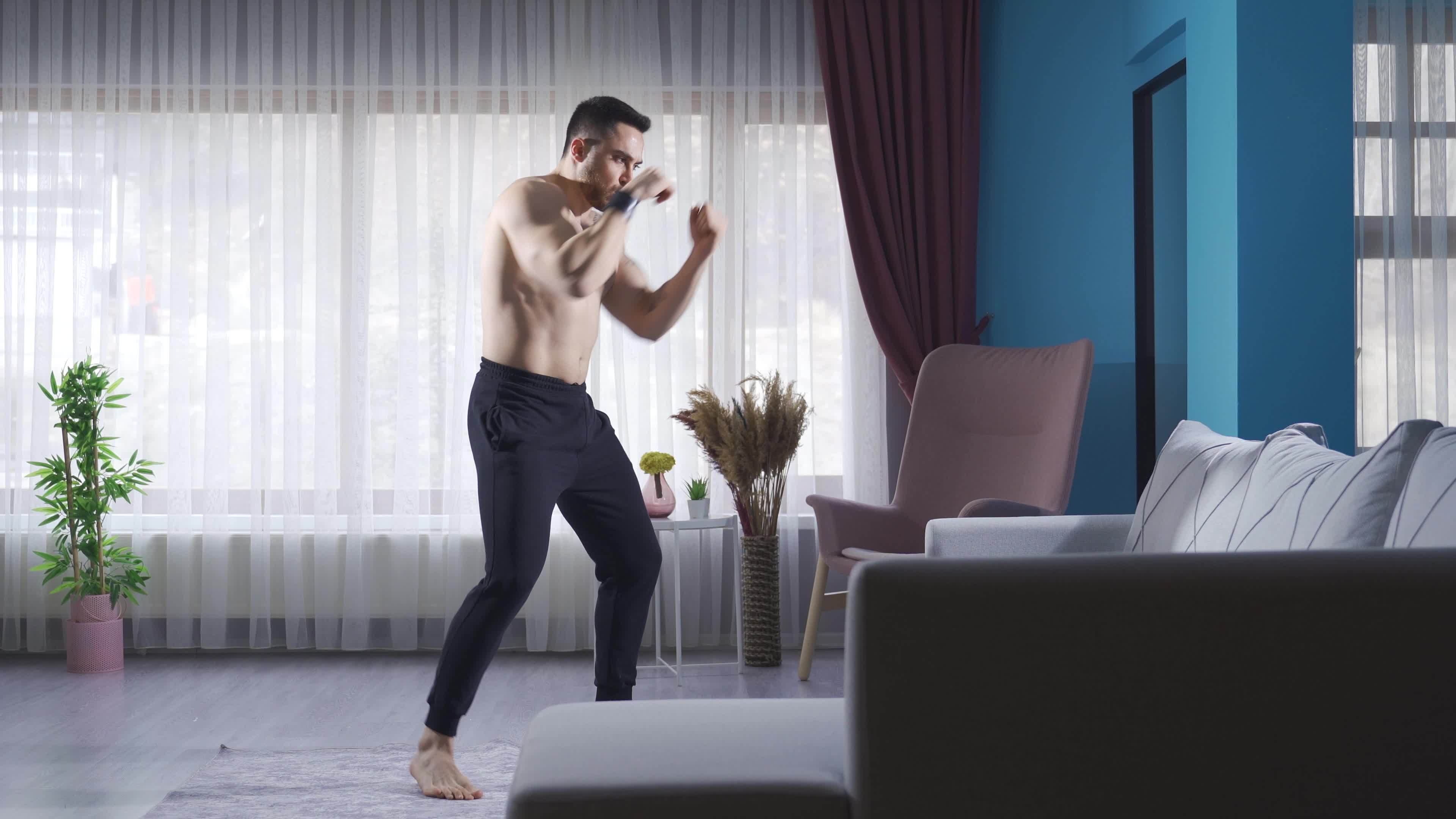 Fit and handsome boxer doing shadow boxing in the gym