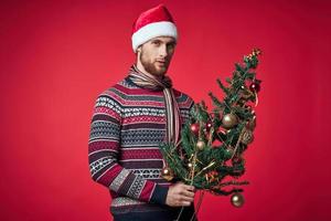 handsome man with a tree in his hands ornaments holiday fun red background photo