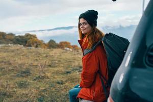 woman hiker in warm clothes resting in the autumn in the mountains near the car photo