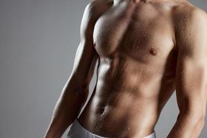 portrait of a athletic man with a pumped-up torso on a gray background photo