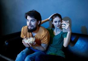 A married couple on the couch watching TV and popcorn indoors photo
