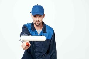 un hombre en un trabajando uniforme un rodillo para pintura paredes en su manos decoración reparar foto