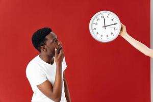 hombre en sorpresa mira a su reloj en un blanco camiseta aislado antecedentes foto