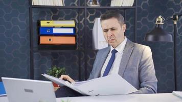 Serious and focused mature businessman looking at paperwork files in office. Focused businessman in office Generates new ideas, looks for solutions. Doubts and difficulties concept. video