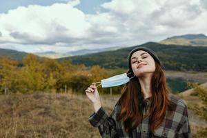 Happy woman took off the medical mask from her face in nature in the forest photo