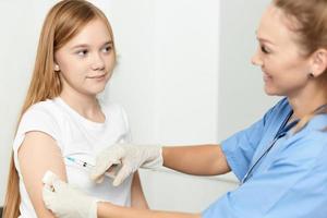 hembra médico dando un inyección a un niña en el mano de un hospital salud codicioso foto