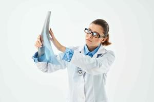 mujer médico en blanco Saco mirando a radiografía diagnósticos de cerca foto