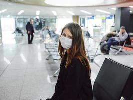 woman with displeased expression wearing medical mask airport waiting flight delay photo