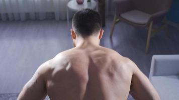 homme développe retour muscles en utilisant équipement à maison. Jeune athlète homme bâtiment retour muscles par étreindre haltère à maison. video