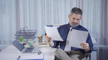 Mature businessman looking at documents working very carefully. Senior businessman working in home office focused and serious looking at paperwork. video