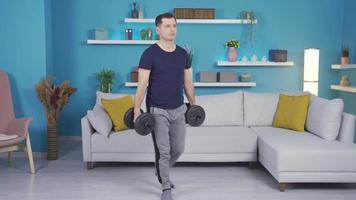 Mature sportsman man exercising using equipment at home. Athlete man trains at home with the help of dumbbells. video