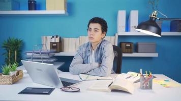 Young man looking around sluggish, unhappy and thoughtful. Young male sitting at his desk looking around with thoughtful and unhappy eyes. video