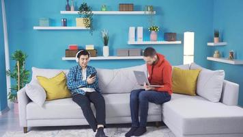 Boy fights competitively on sofa with brother at home because they don't get along Young man not caring about his little brother sitting on the sofa. Sibling rivalry. video