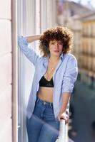 Woman touching curly hair on balcony photo