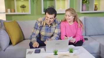 ouderen volwassen paar berekenen rekeningen en kosten uitglijden gebruik makend van laptop Bij huis. video