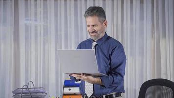 mature homme d'affaire travail Heureusement et pacifiquement dans le sien bureau. content et agréable mature homme d'affaire travail sur ordinateur portable, dactylographie sur clavier. video