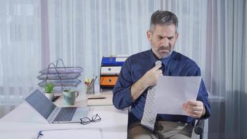 Depressed mature businessman receives bad news on paperwork he is reading. Mature businessman reading bad and annoying articles gets sick, takes a loss, on the verge of bankruptcy, debt receipts. video