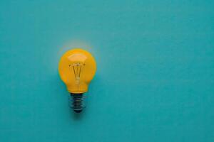 flat lay photo of yellow bulb on turquoise blue background. Illustration