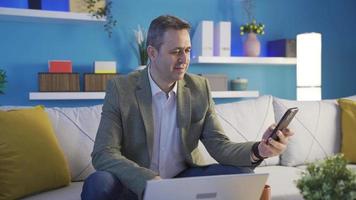Smiling mature man using smartphone indoors. Businessman mobile technology user searching information online, sending messages at home, using social media apps. video
