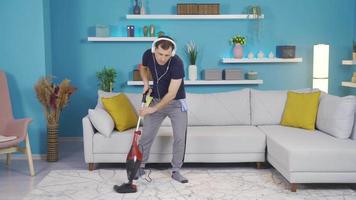 The man is cleaning his house, and suddenly he immerses himself in music, thinks of the broom in his hand like a guitar, and starts to make funny moves. video