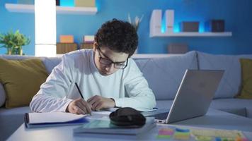 knap en geslaagd mannetje leerling aan het studeren Bij huis laat Bij nacht. de mannetje leerling, wie geeft over zijn studies en succes, studies dag en nacht. video