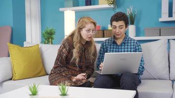 jong Mens gebruik makend van laptop met zijn moeder Bij huis. jong Mens tonen iets naar zijn moeder Aan laptop scherm, ze zijn ruzie maken over een onderwerp. video