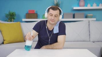 Man involuntarily, unhappy, listening to music with headphones while cleaning. Depressed man involuntarily wiping his coffee table while listening to music with headphones. video