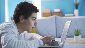 tonåring manlig sökande de internet och webbplatser. Lycklig och glad tonåring manlig använder sig av social media, virtuell värld och internet från bärbar dator på Hem. video