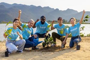 equipo de joven y diversidad voluntario trabajador grupo disfrutar Caritativo social trabajo al aire libre en árbol bosque plantando ong trabajo para luchando clima cambio y global calentamiento en el línea costera habitat proyecto foto