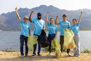 equipo de joven y diversidad voluntario trabajador grupo disfrutar Caritativo social trabajo al aire libre en limpieza arriba basura y residuos separación proyecto a el río playa foto